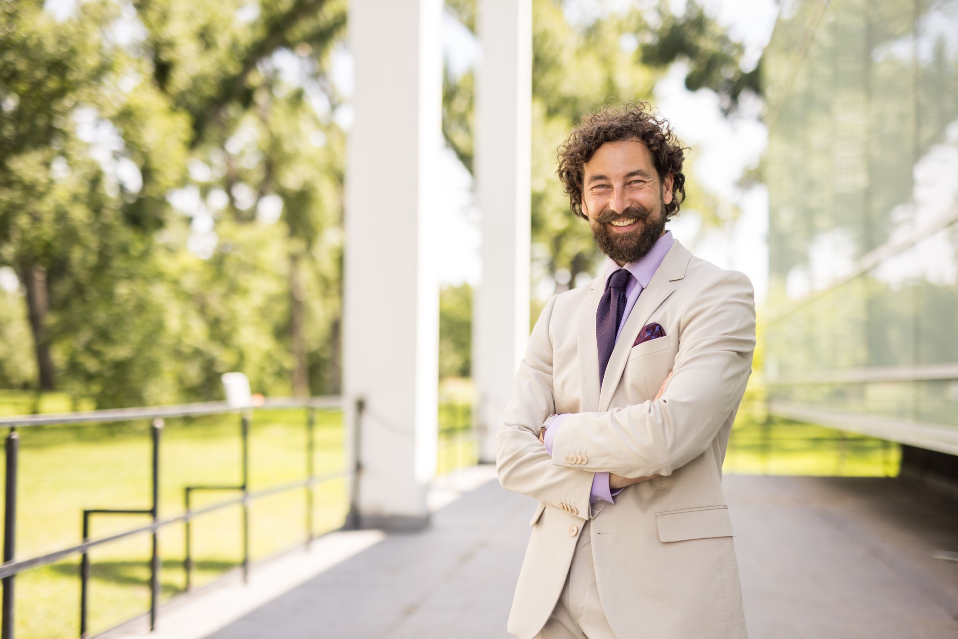 Smiling businessman with crossed arms posing in a park